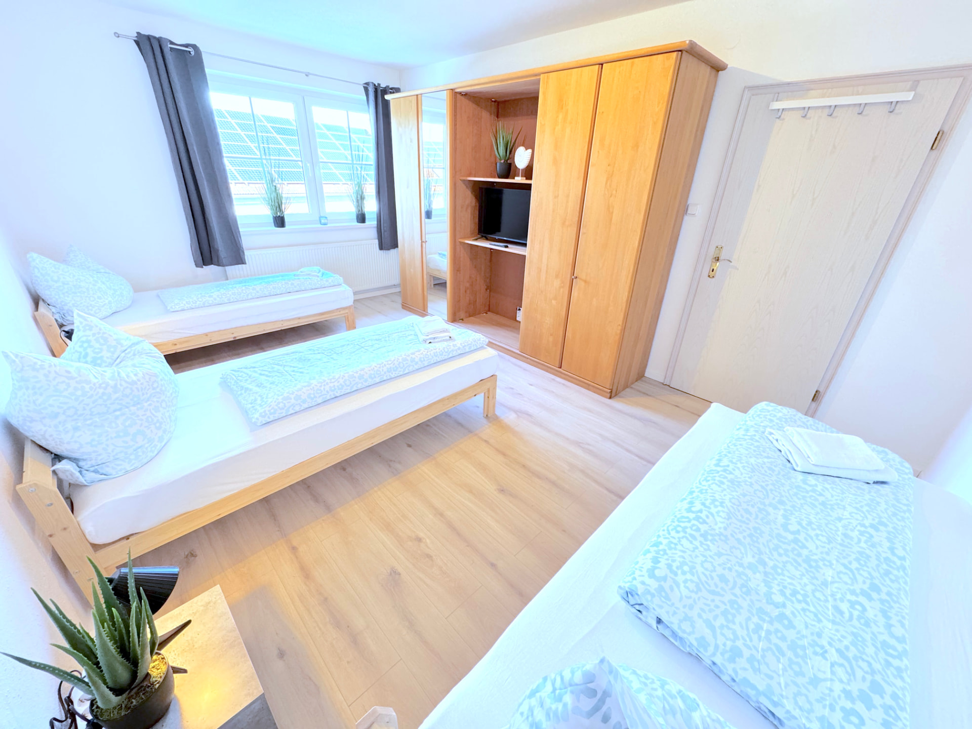 Apartment II in Dingolfing – Schlafzimmer mit vier Betten, Schrank und TV