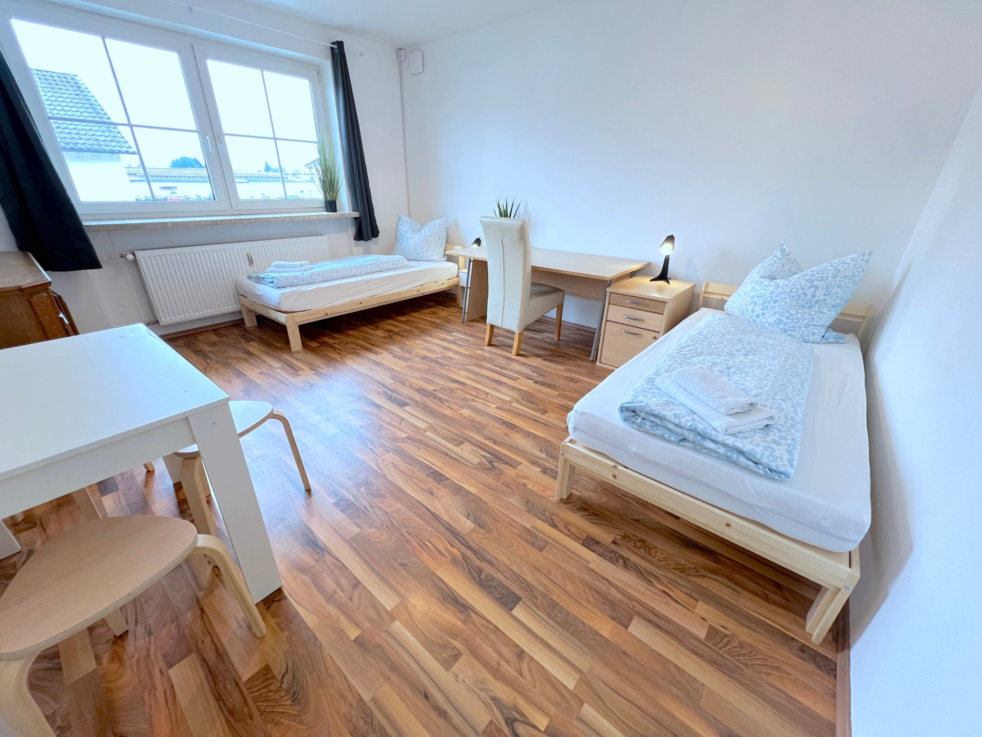 Apartment V in Dingolfing – Heller Schlafraum mit zwei Einzelbetten, Schreibtisch und Esstisch