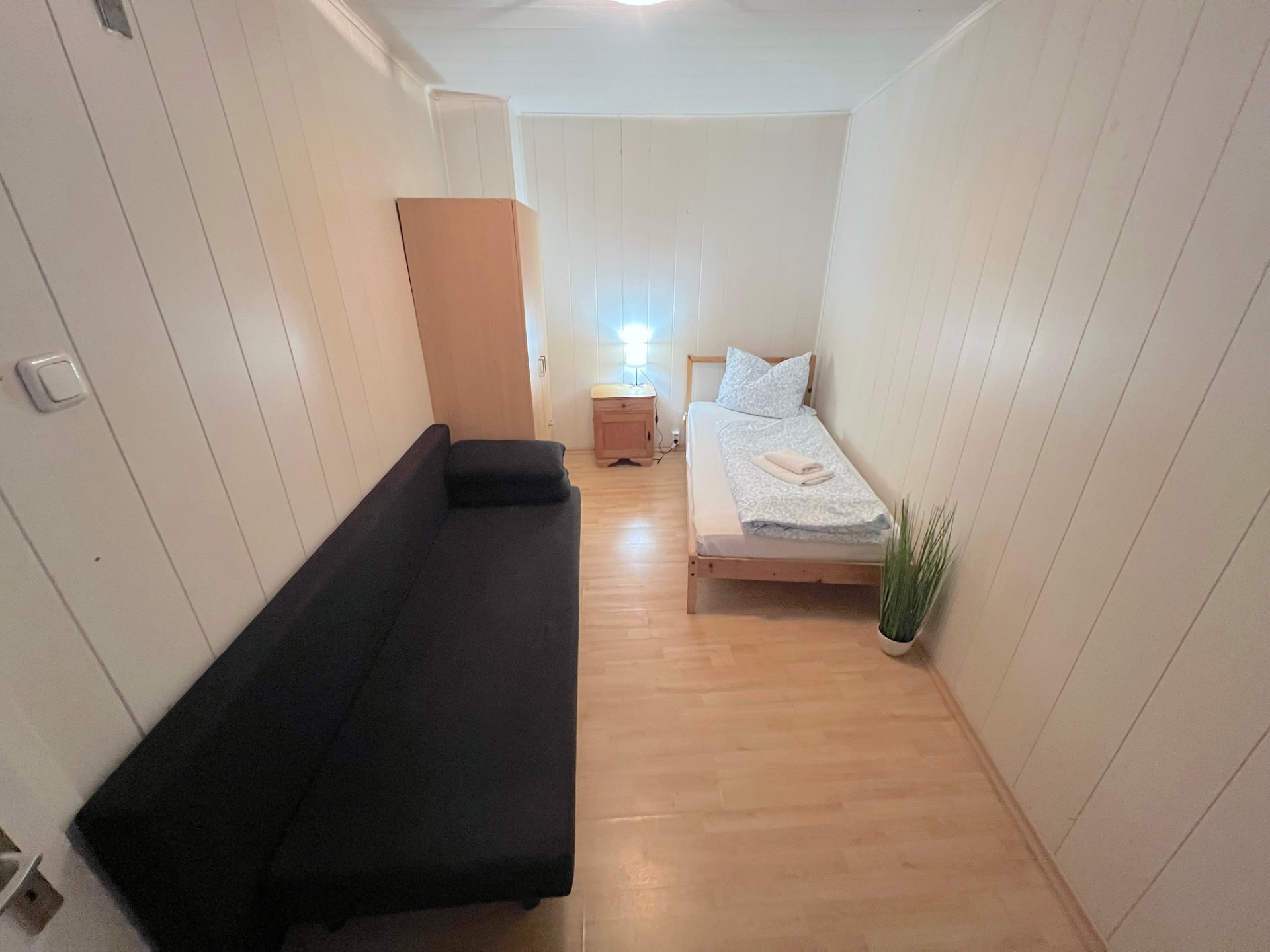 WG-Zimmer mit Einzelbett, Sofa, Kleiderschrank und Nachttisch in Großköllnbach