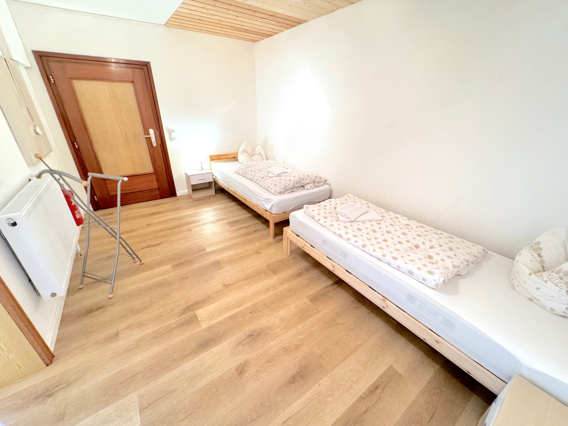 Helles Zwei-Bett-Zimmer mit Holzdecke, Vinylboden und Nachttisch in Apartment I Griesbach