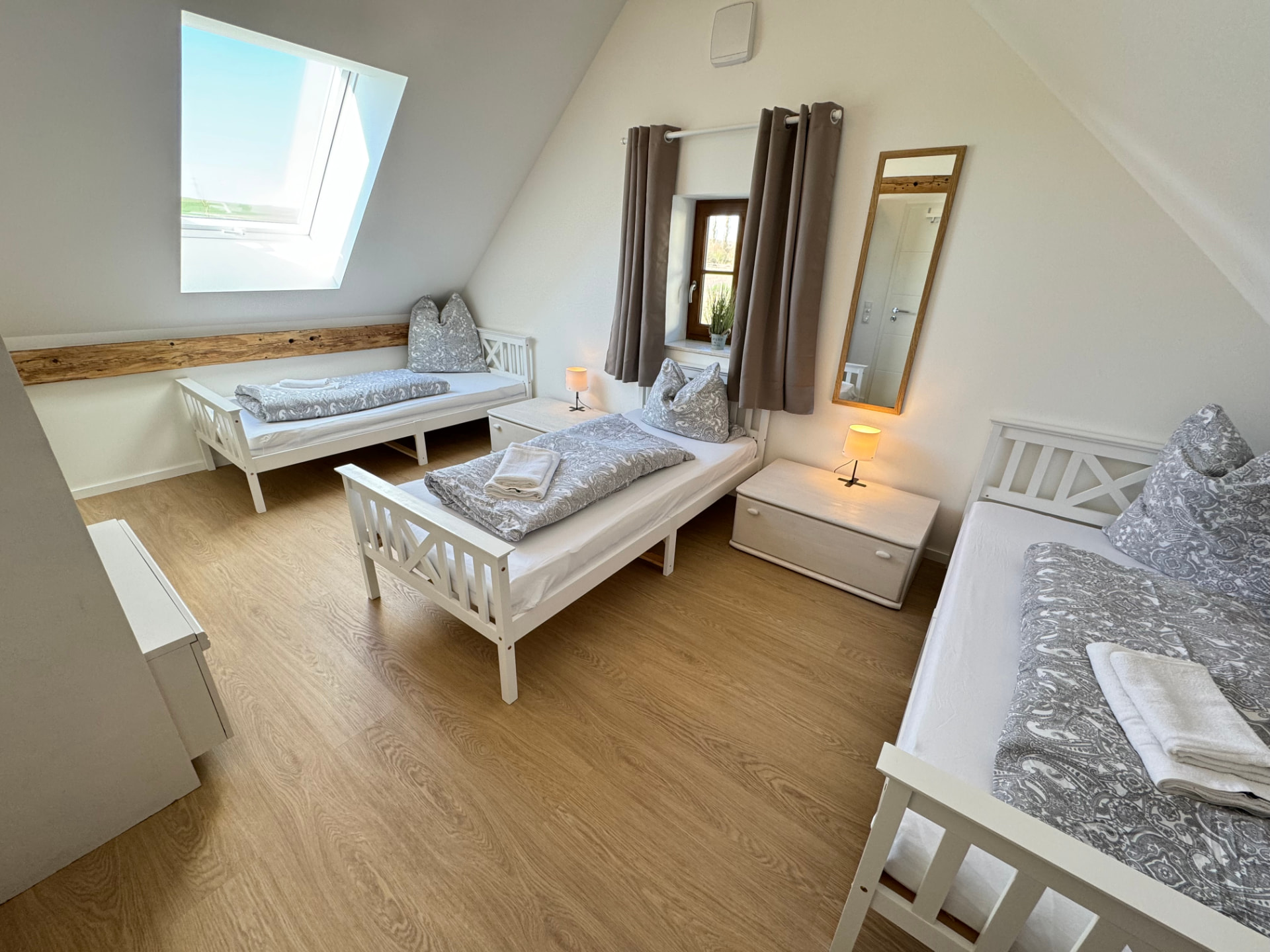 Drei-Bett-Zimmer mit Einzelbetten, Dachfenster und Spiegel in Apartment 3 Gottfrieding