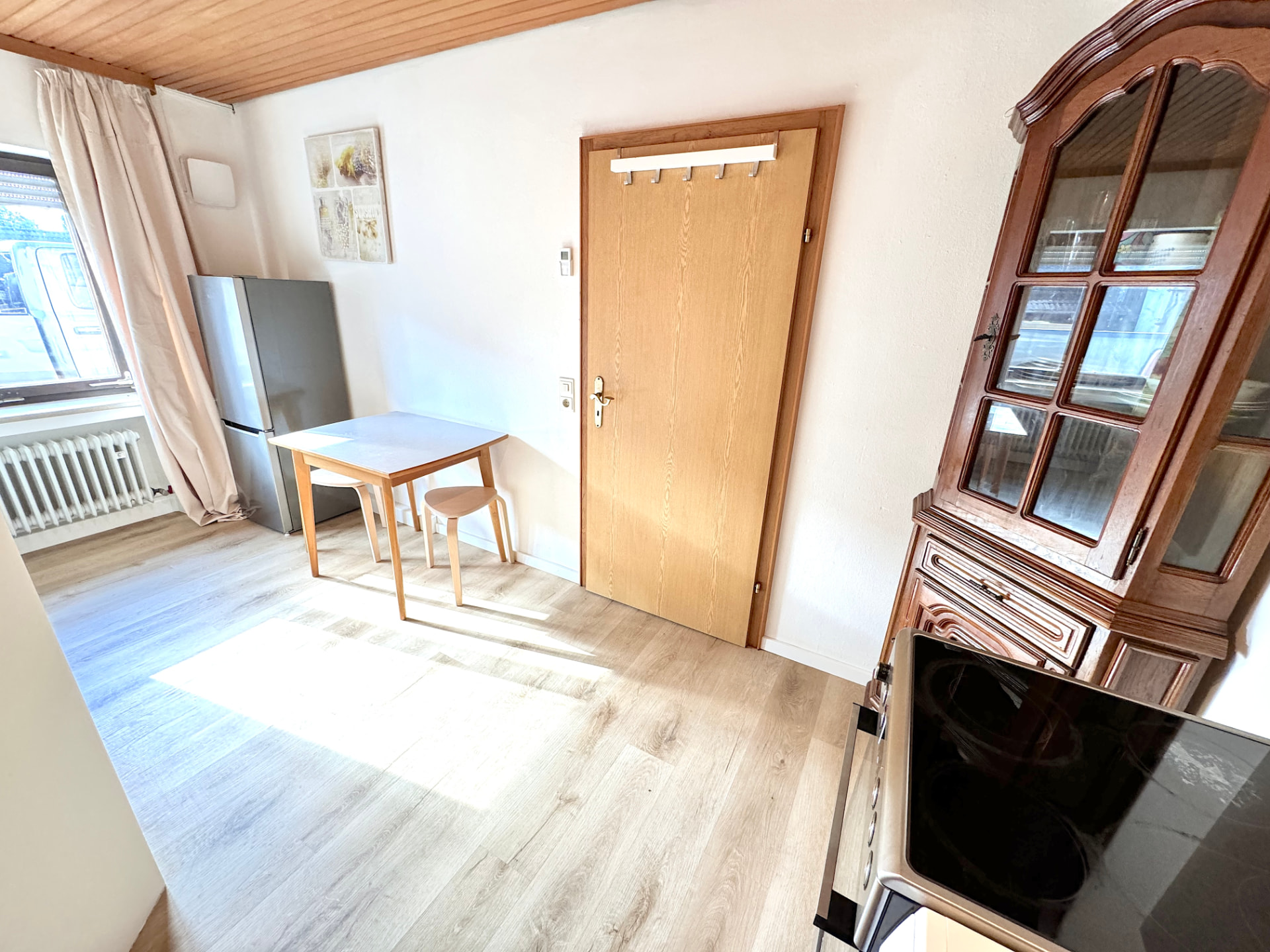 Essbereich mit Tisch, Kühlschrank, Fenster und Garderobe in Apartment I Griesbach