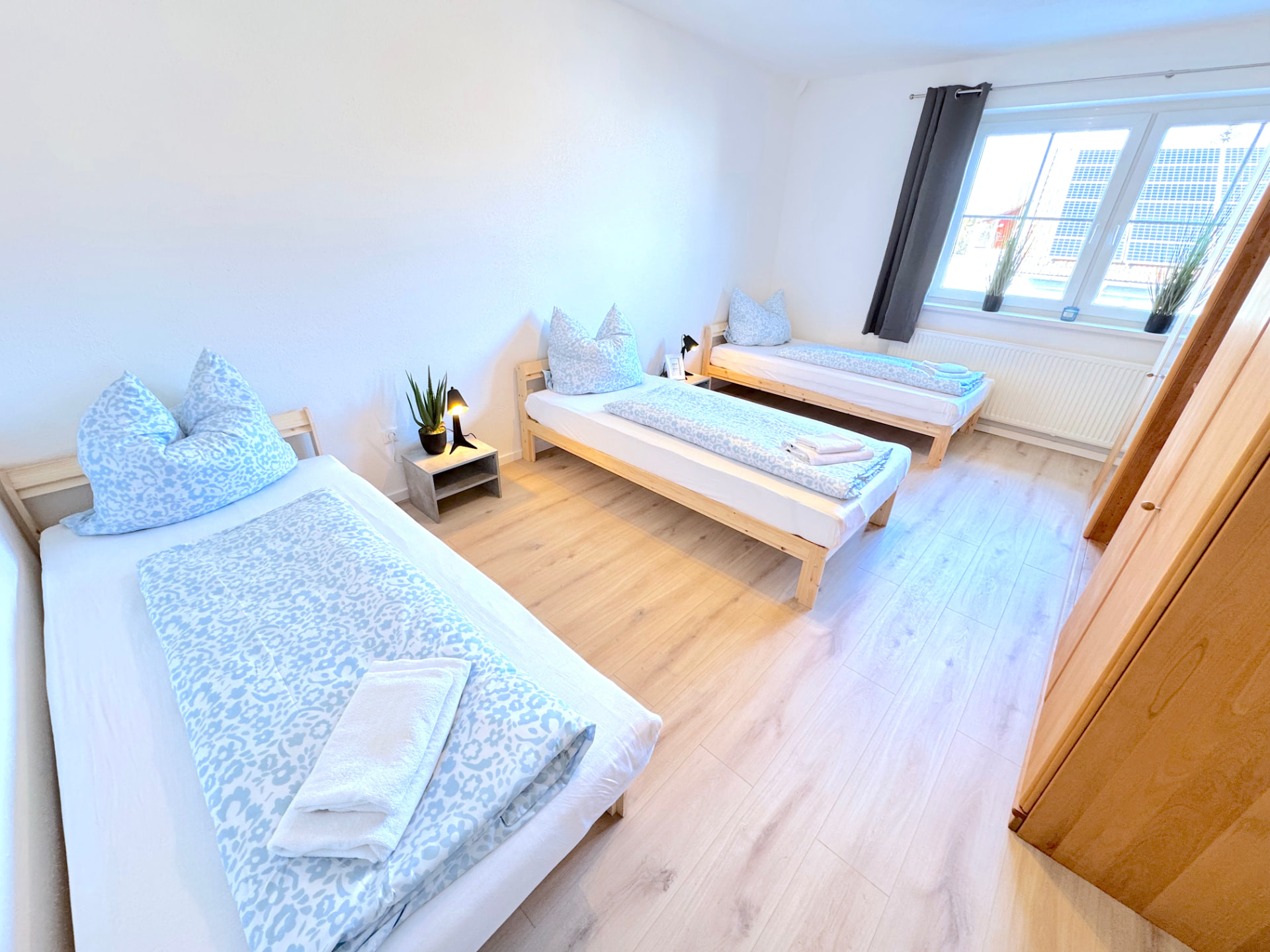 Apartment II in Dingolfing – Heller Schlafraum mit drei Betten und Kleiderschrank