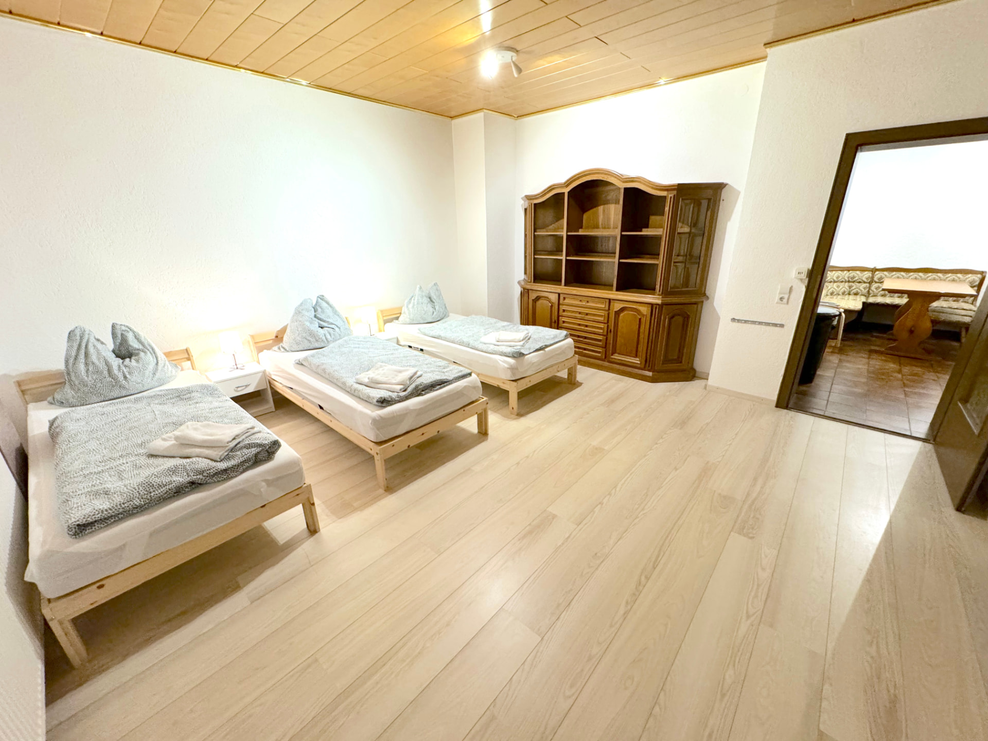 Apartment II in Kronwieden – Schlafraum mit drei Betten, Buffetschrank und Durchgang zur Küche