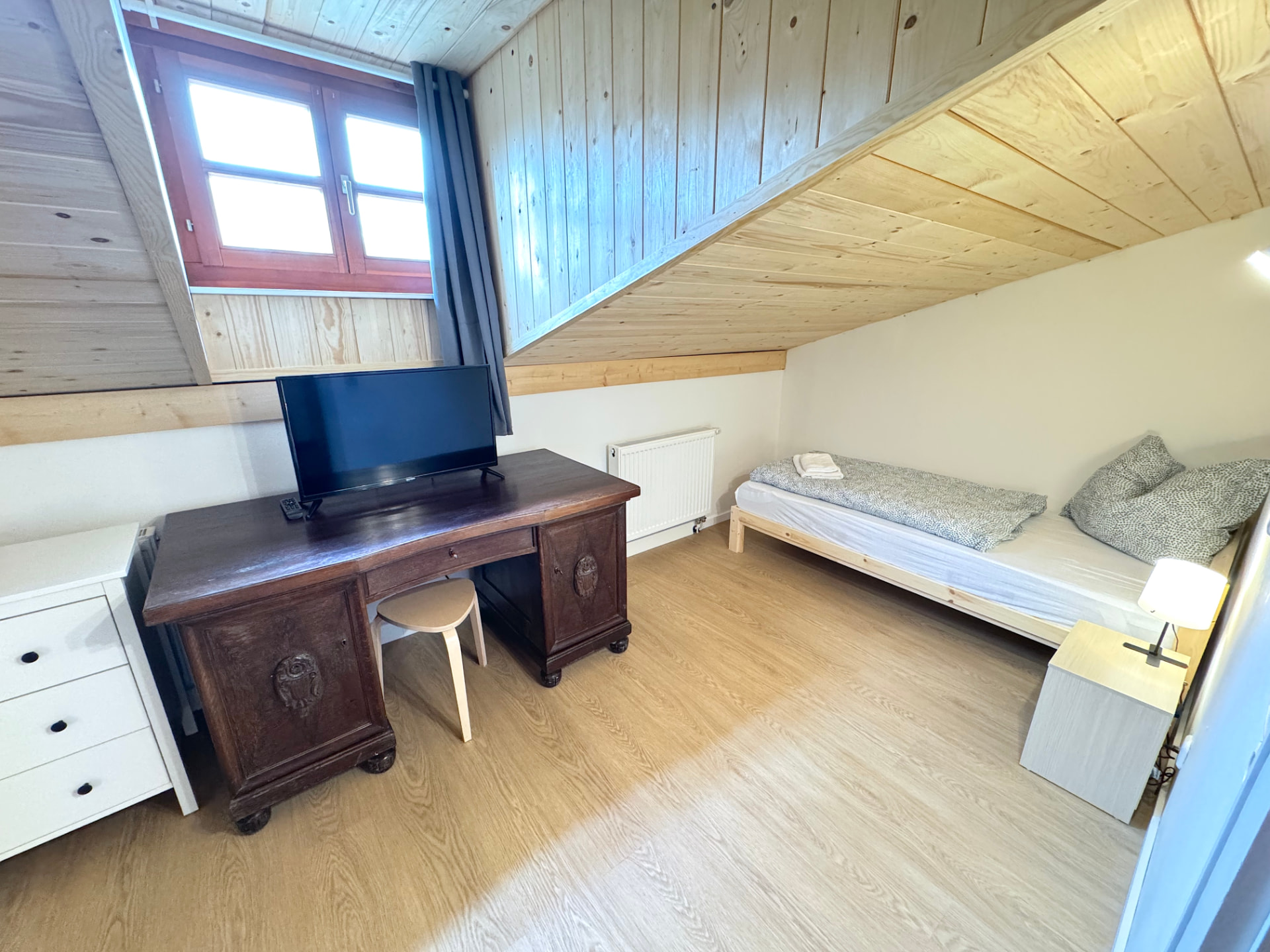Apartmenthaus in Frontenhausen – Dachzimmer mit Bett, Schreibtisch, TV und Holzverkleidung