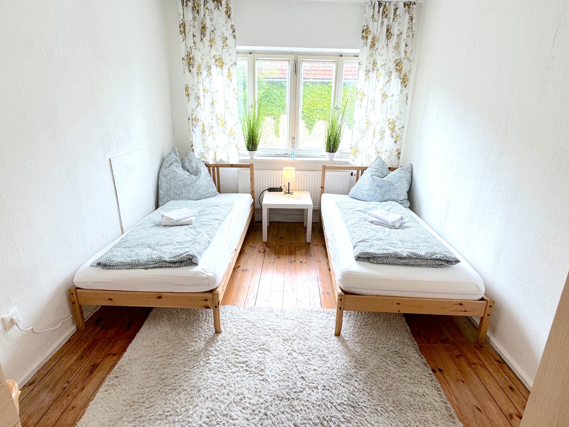 Schlafzimmer mit zwei Einzelbetten am Fenster und Dielenboden im Apartmenthaus Großköllnbach