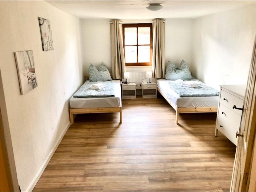 Zwei-Bett-Zimmer mit Holzbetten, Nachttischen und Kommode – Vilstal Apartment 1 in Reisbach/Altersberg