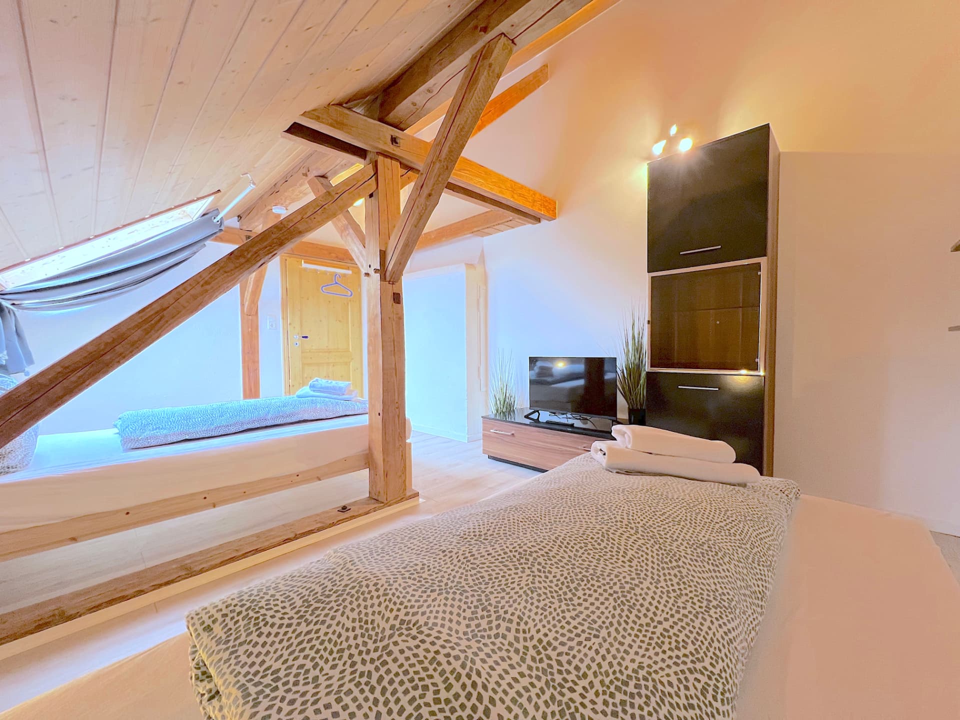 Apartment III in Dingolfing – Schlafbereich unter dem Dach mit TV und Schrank