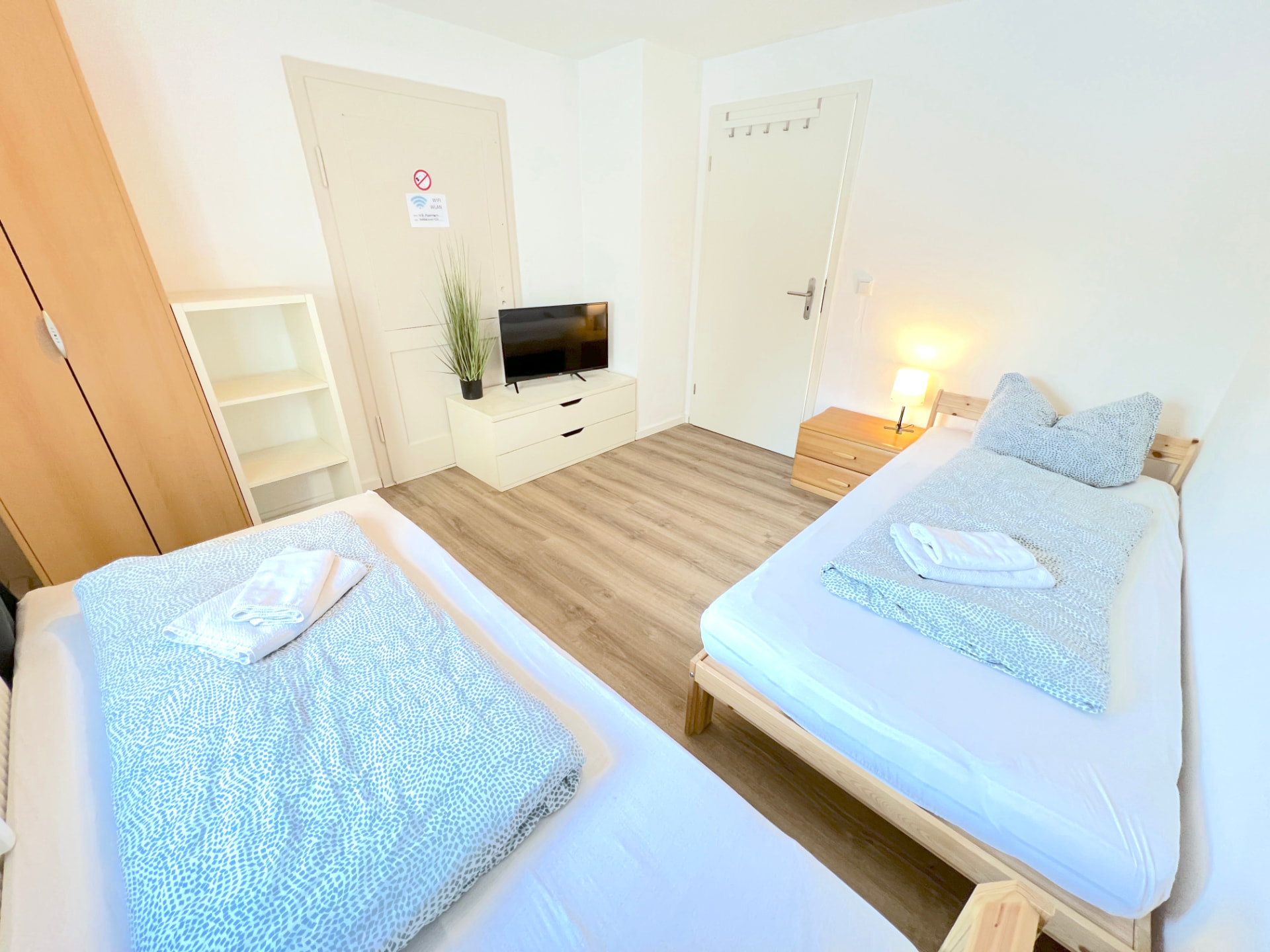 Zimmer mit zwei Betten, Kleiderschrank, Regal und TV in Apartment II Großköllnbach