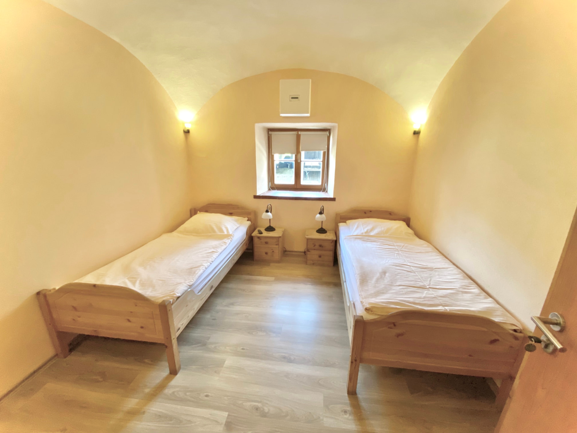 Zwei-Bett-Zimmer mit Gewölbedecke, Holzbetten und Nachttischen in Apartment 0 Gottfrieding