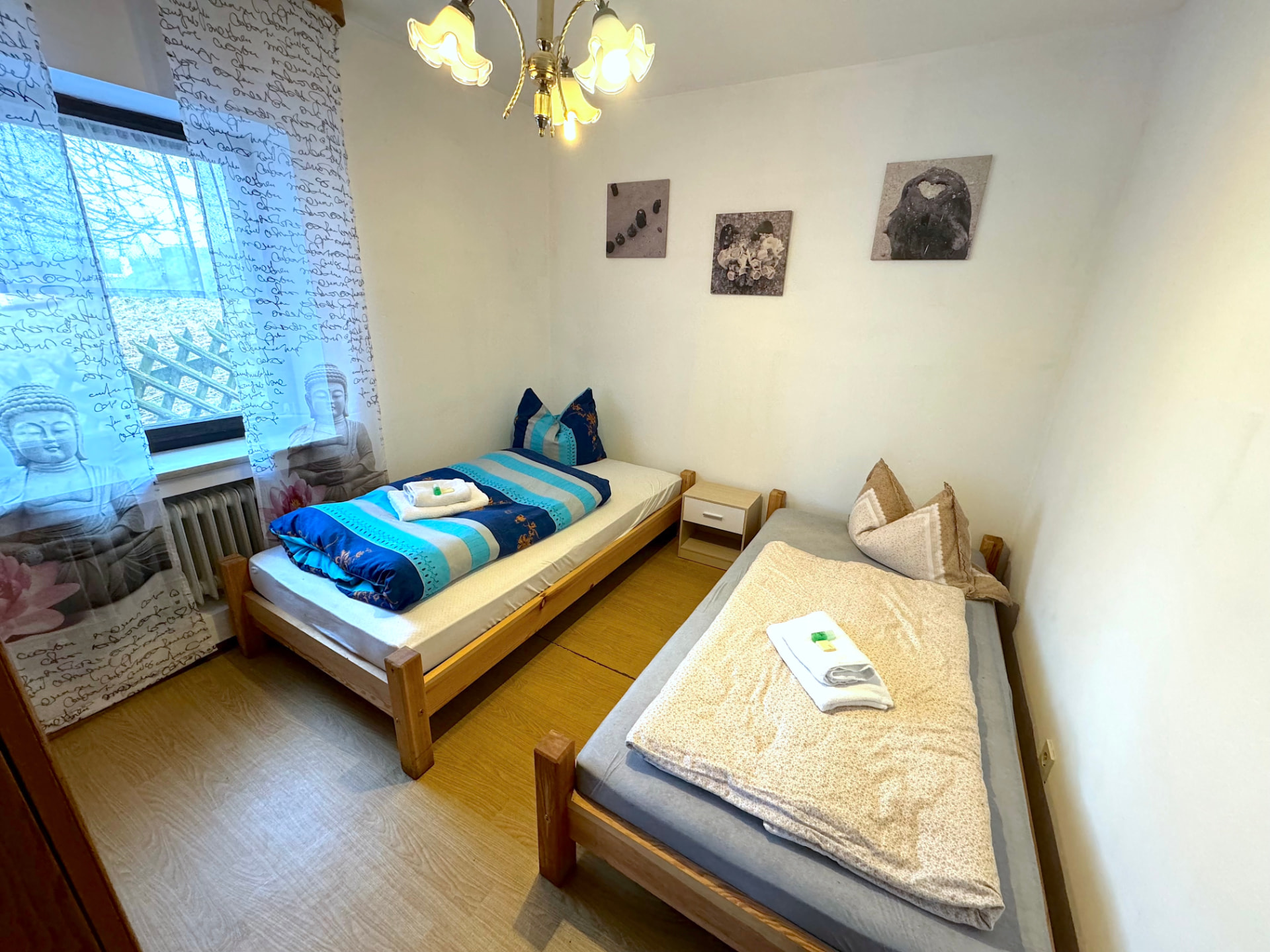 Schlafzimmer mit zwei Einzelbetten, Nachttisch und Bildern an der Wand in Apartment II Griesbach