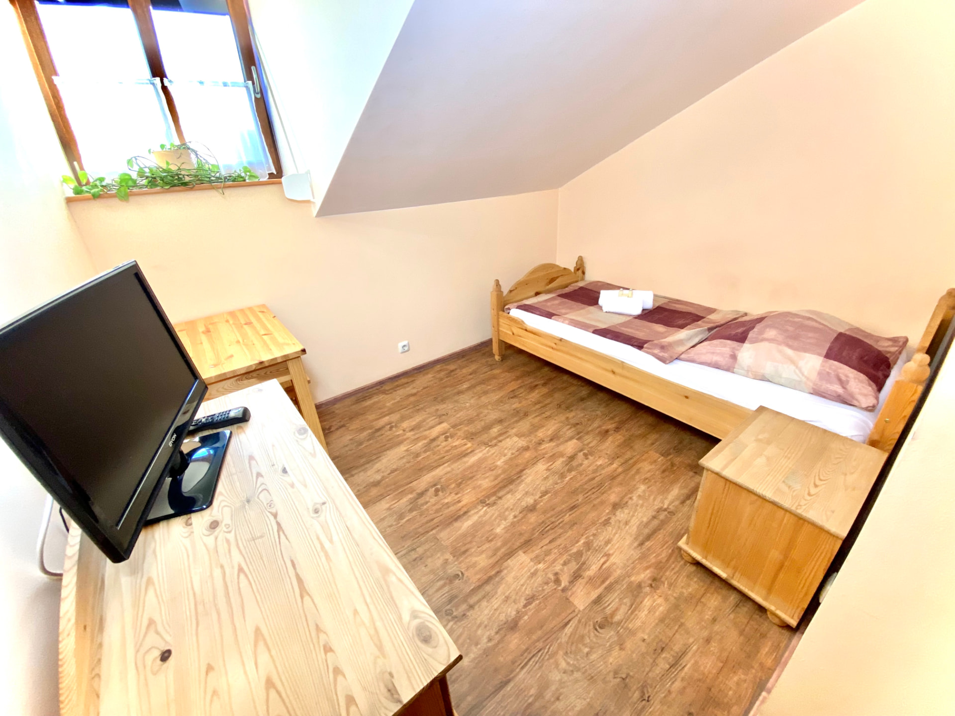 Einzelzimmer mit Holzbett, Schreibtisch und TV in der Pension Laurent Ranch Gottfrieding