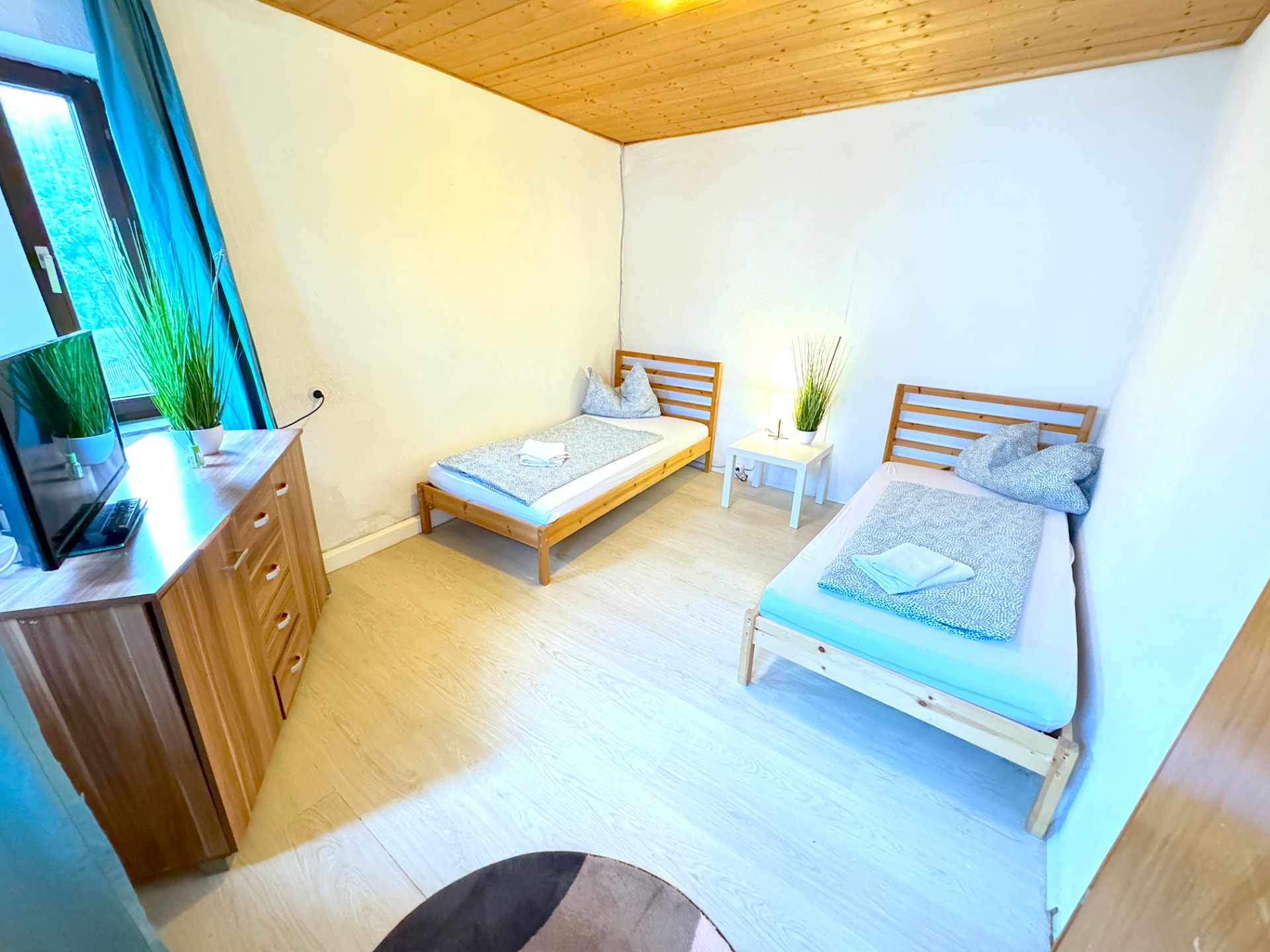 Helles Schlafzimmer mit zwei Einzelbetten, Holzdecke, TV und Kommode in Großköllnbach