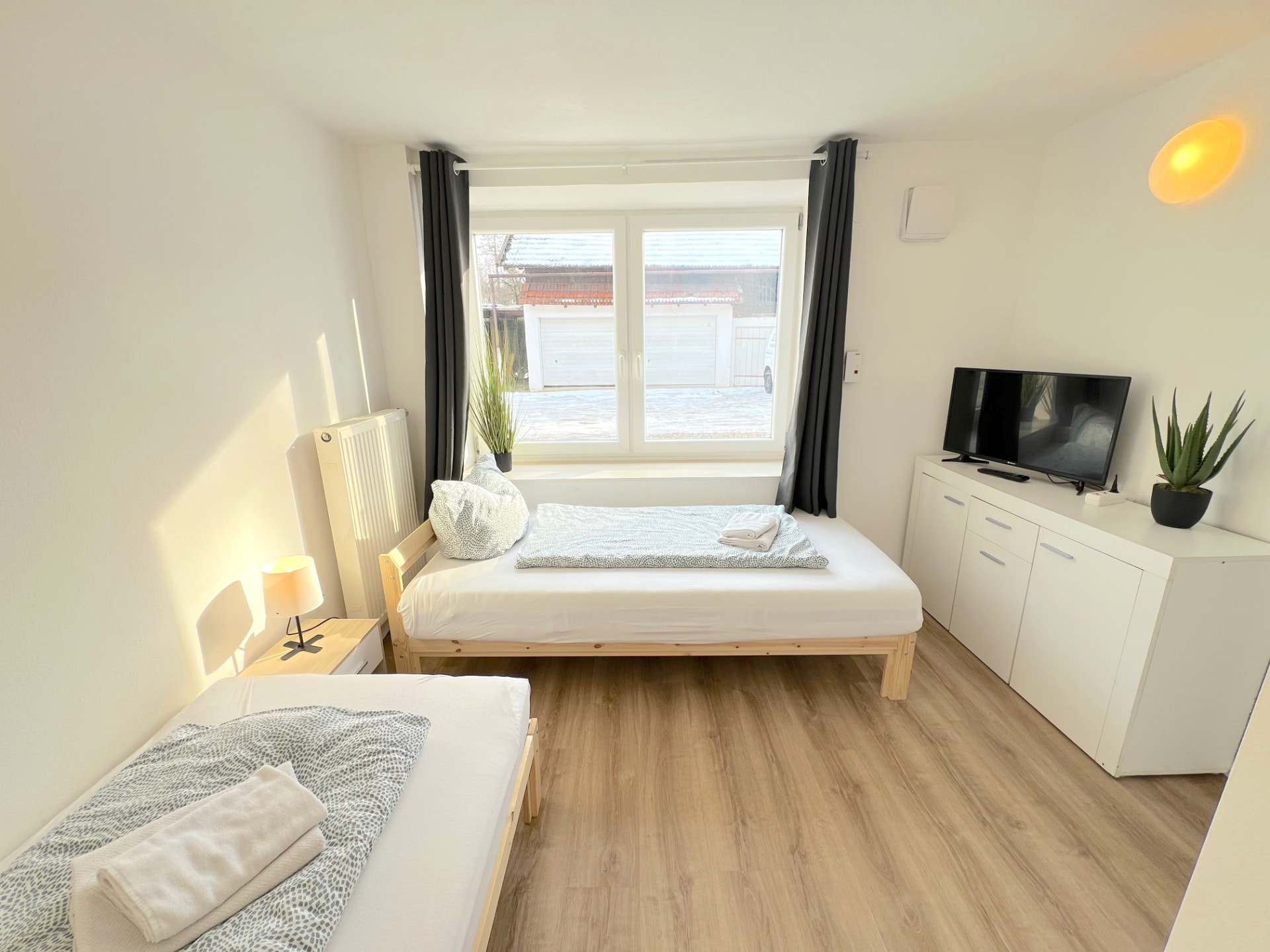 Zimmer mit zwei Einzelbetten, TV auf Sideboard und Fenster in Apartment II Großköllnbach