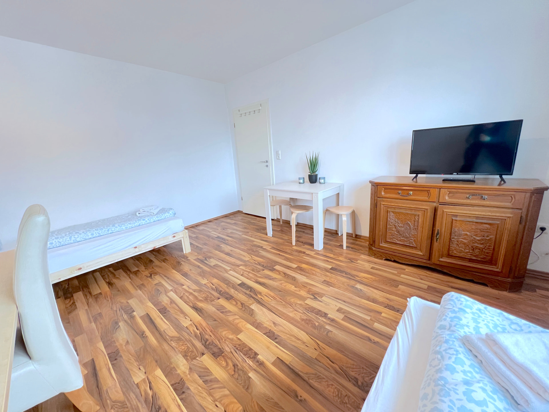Apartment V in Dingolfing – Wohn- und Schlafbereich mit TV, Sideboard und Esstisch