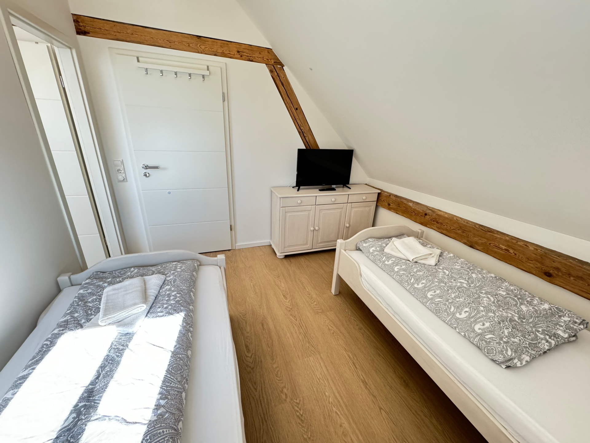 Zwei-Bett-Zimmer mit TV-Kommode und Holzbalken in Apartment 3 Gottfrieding