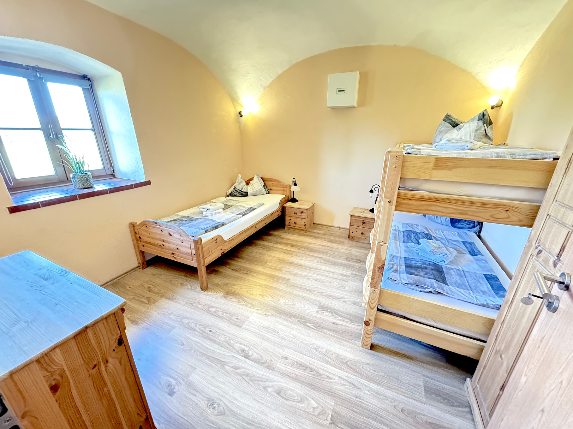 Drei-Bett-Zimmer mit Etagenbett, Einzelbett und Fenster in Apartment 0 Gottfrieding