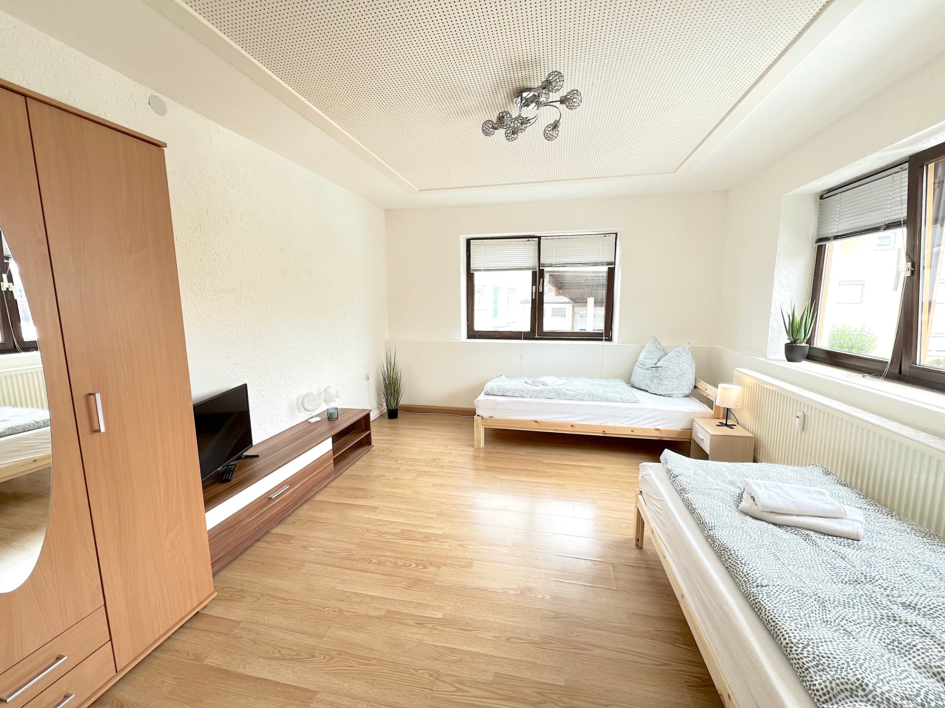 Geräumiges Zimmer mit zwei Einzelbetten, Kleiderschrank und TV-Board in Apartment I Großköllnbach