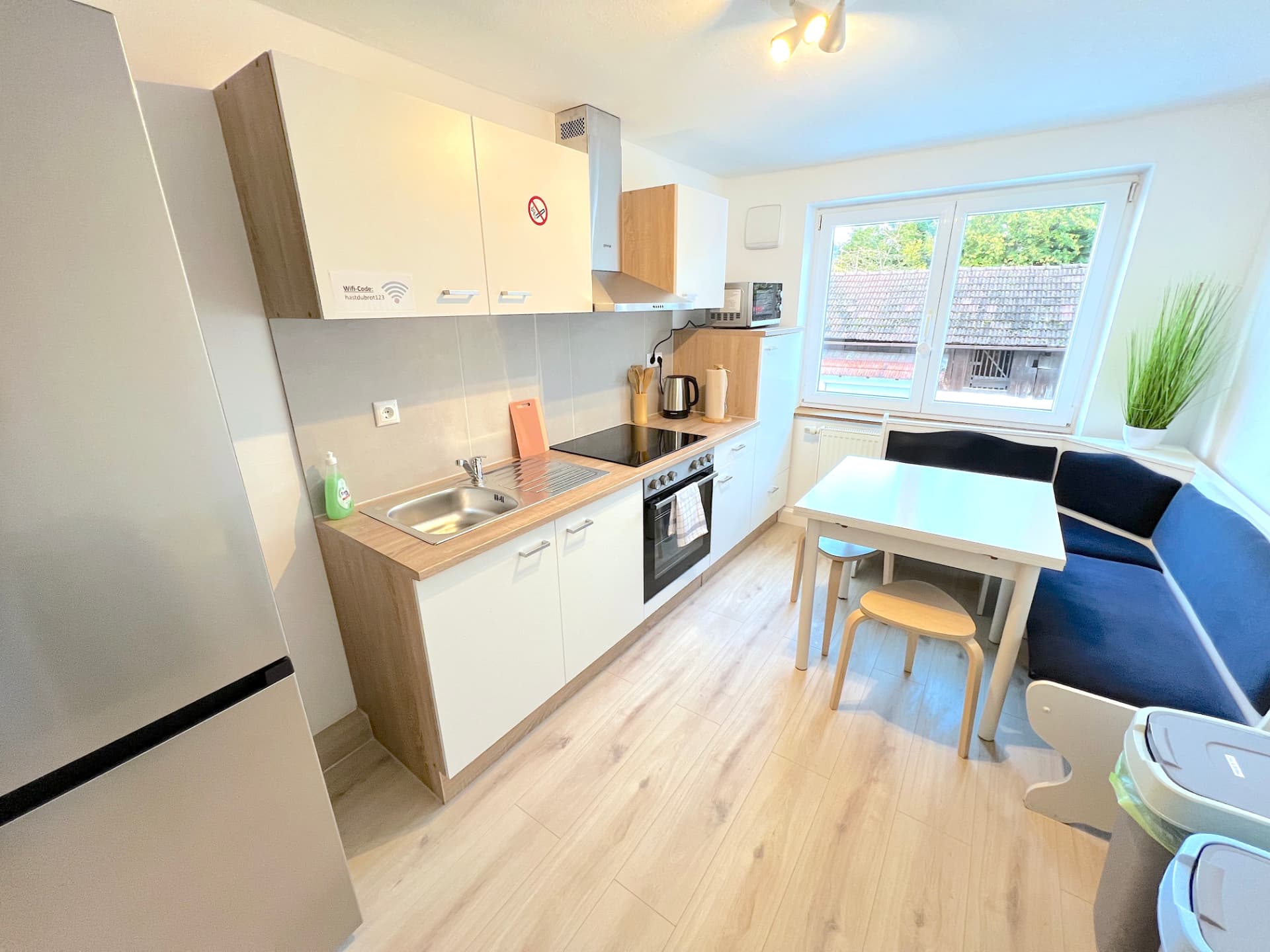 Küche mit Elektroherd, Spüle, Mikrowelle und Essbereich mit Eckbank in Apartment III Großköllnbach