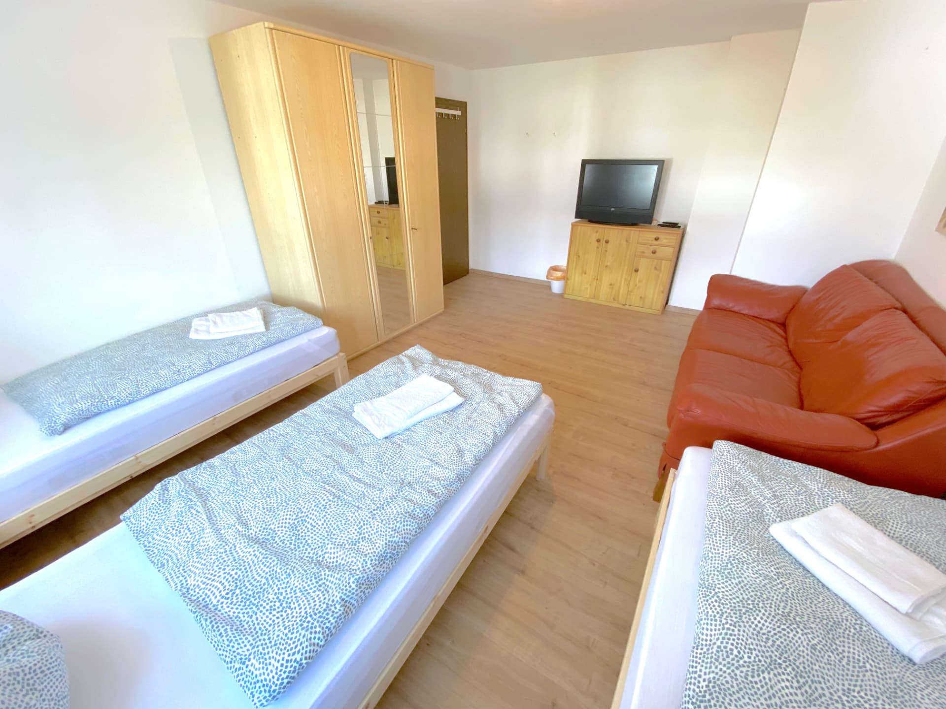 Apartment IV in Kronwieden – Zimmer mit drei Betten, Kleiderschrank, TV und Ledersofa