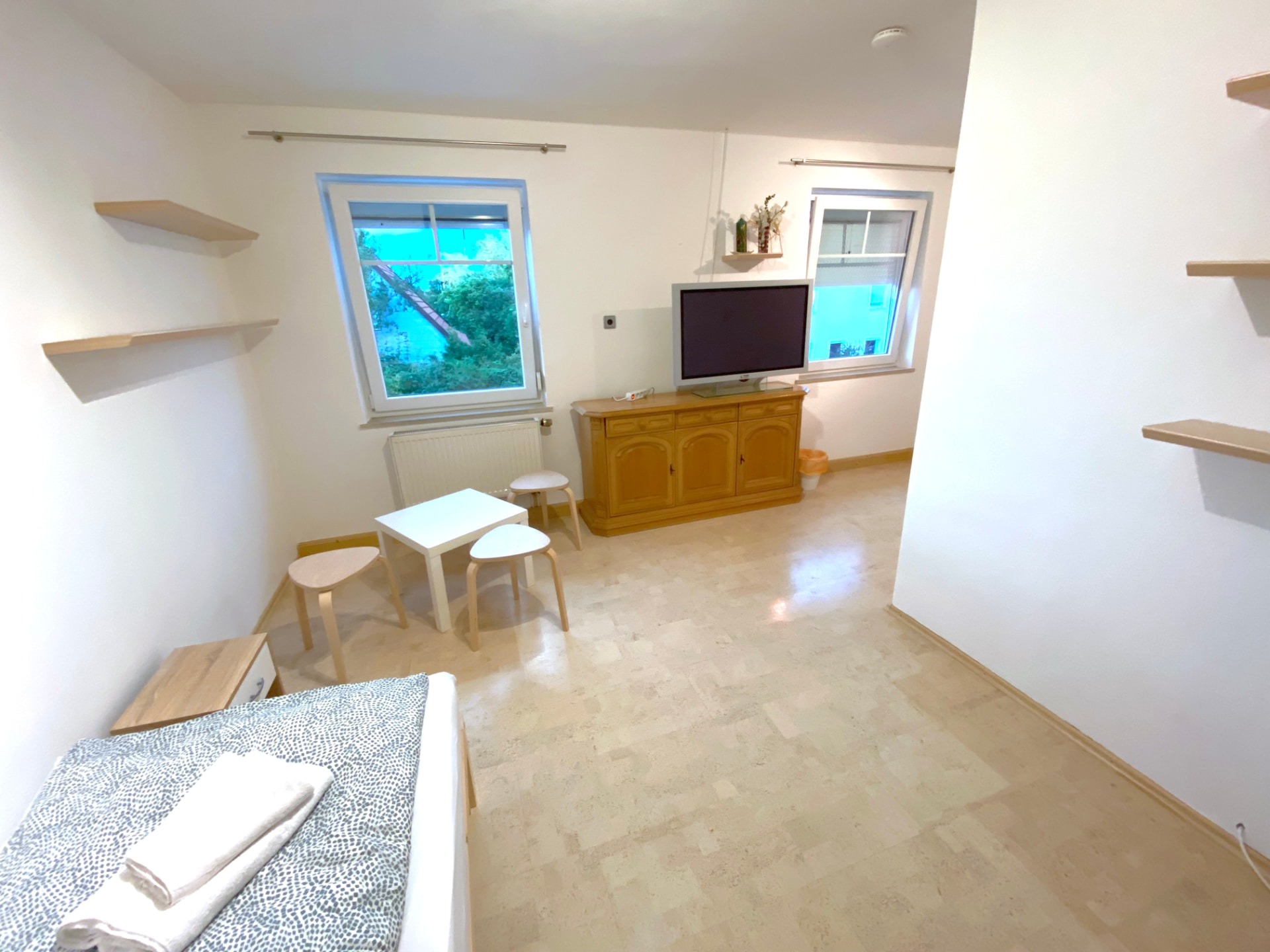 Apartment III in Kronwieden – Wohnraum mit TV, Sideboard, Tisch und Hockern
