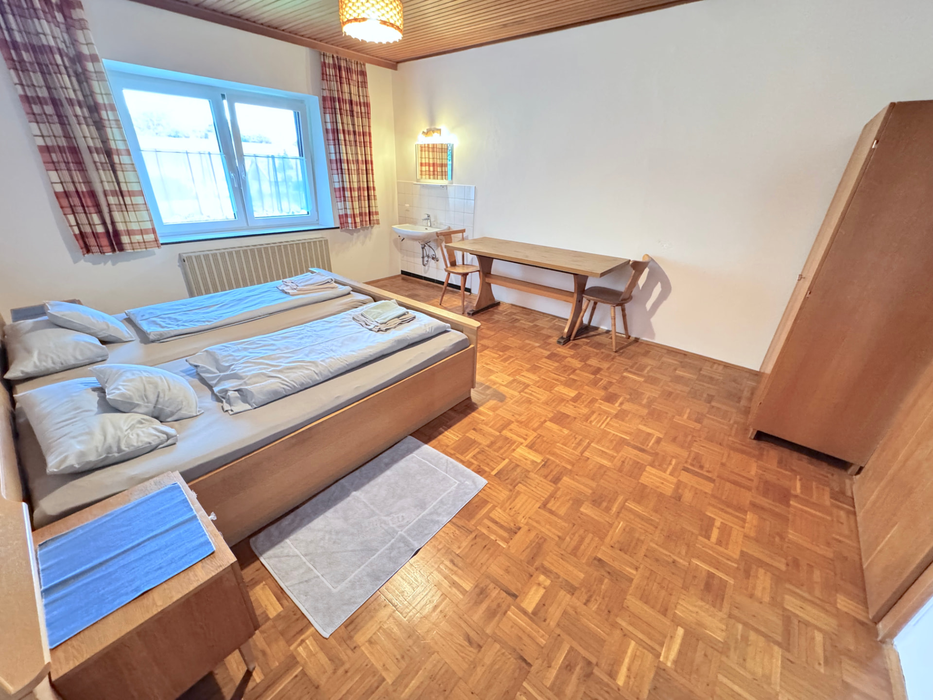 Zwei-Bett-Zimmer mit Waschbecken, Esstisch und Kleiderschrank in Apartment III Mettenhausen