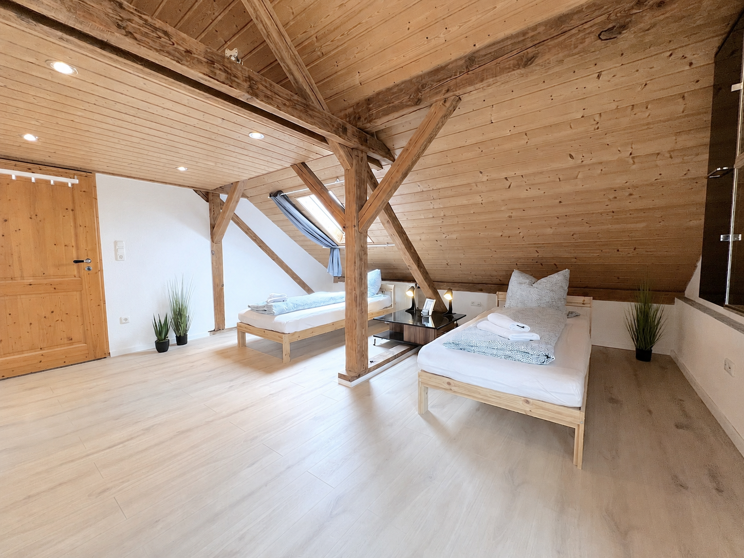 Helles Dachgeschoss-Zimmer mit Holzbalken, zwei Betten und freundlicher Holzausstattung