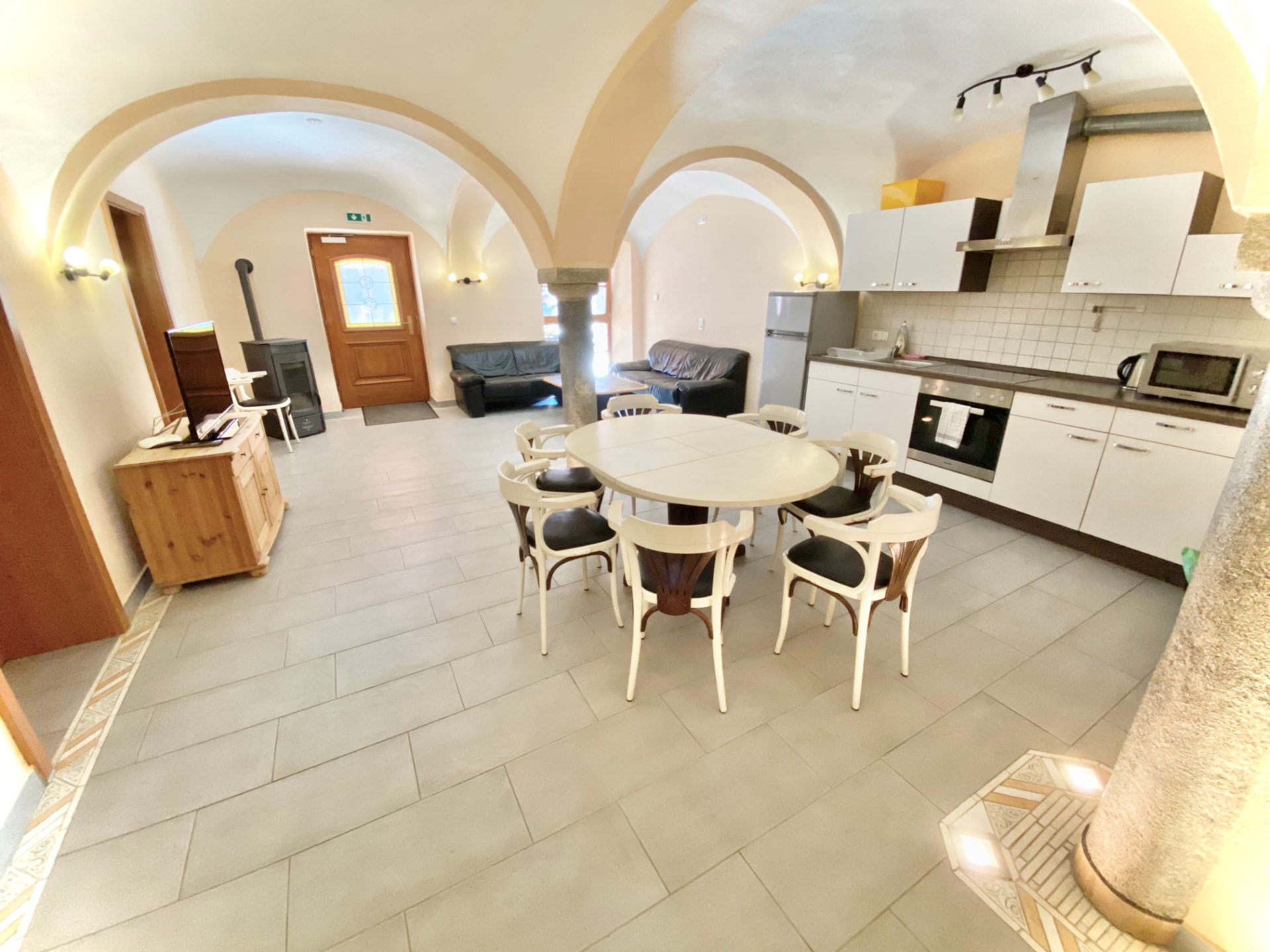 Wohn- und Essbereich mit Gewölbedecke, offener Küche, Esstisch und Ledersofas in Apartment 0 Gottfrieding