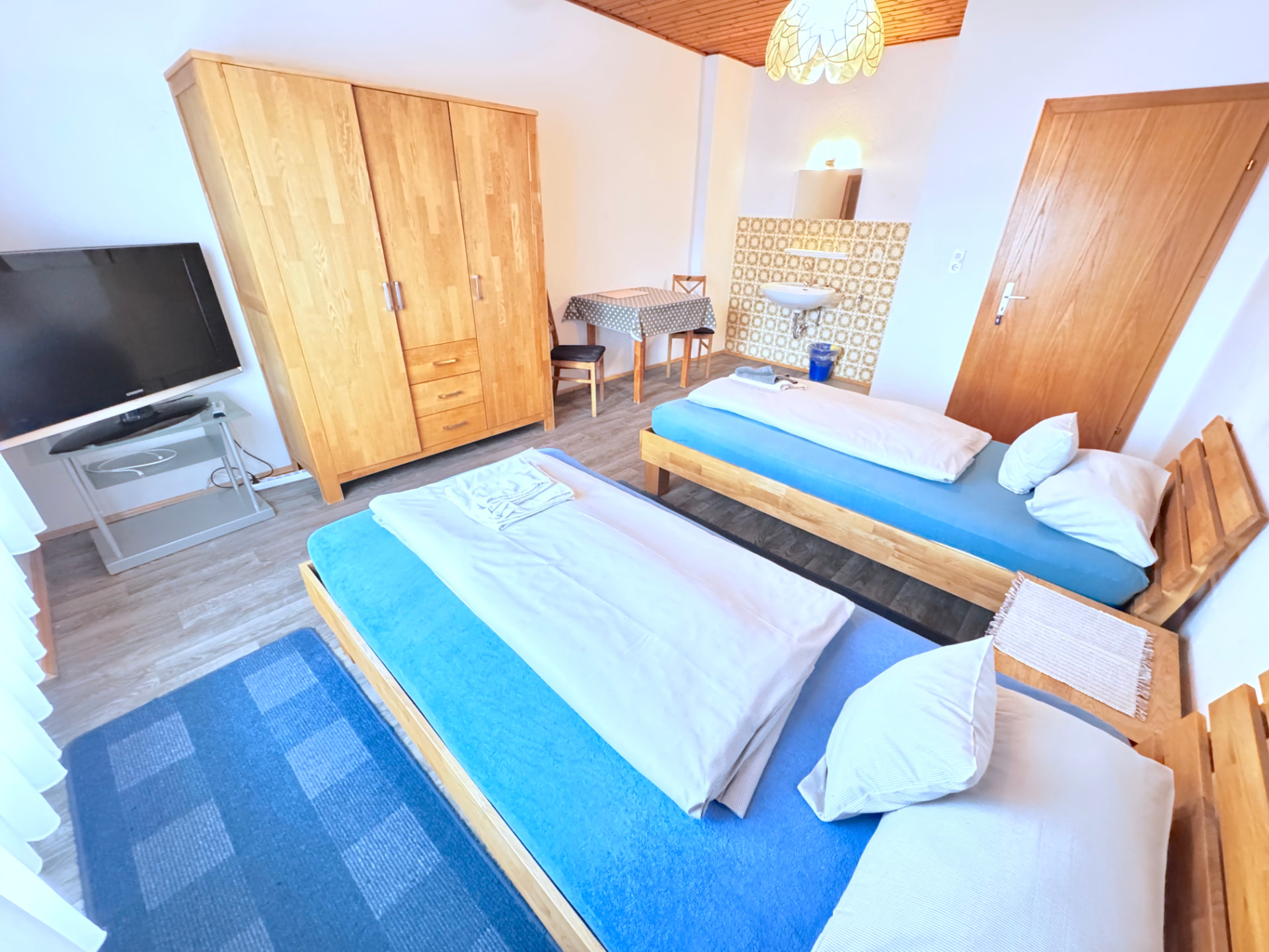 Zimmer mit zwei Einzelbetten, TV, Kleiderschrank und Waschbecken in Apartment III Mettenhausen