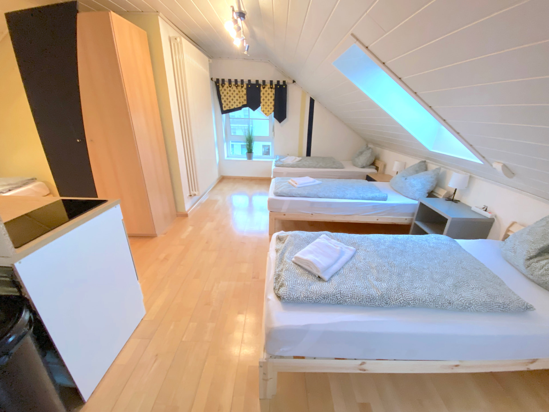 Studio-Apartment V in Kronwieden – Schlafbereich mit drei Betten, Kleiderschrank und Küchenzeile