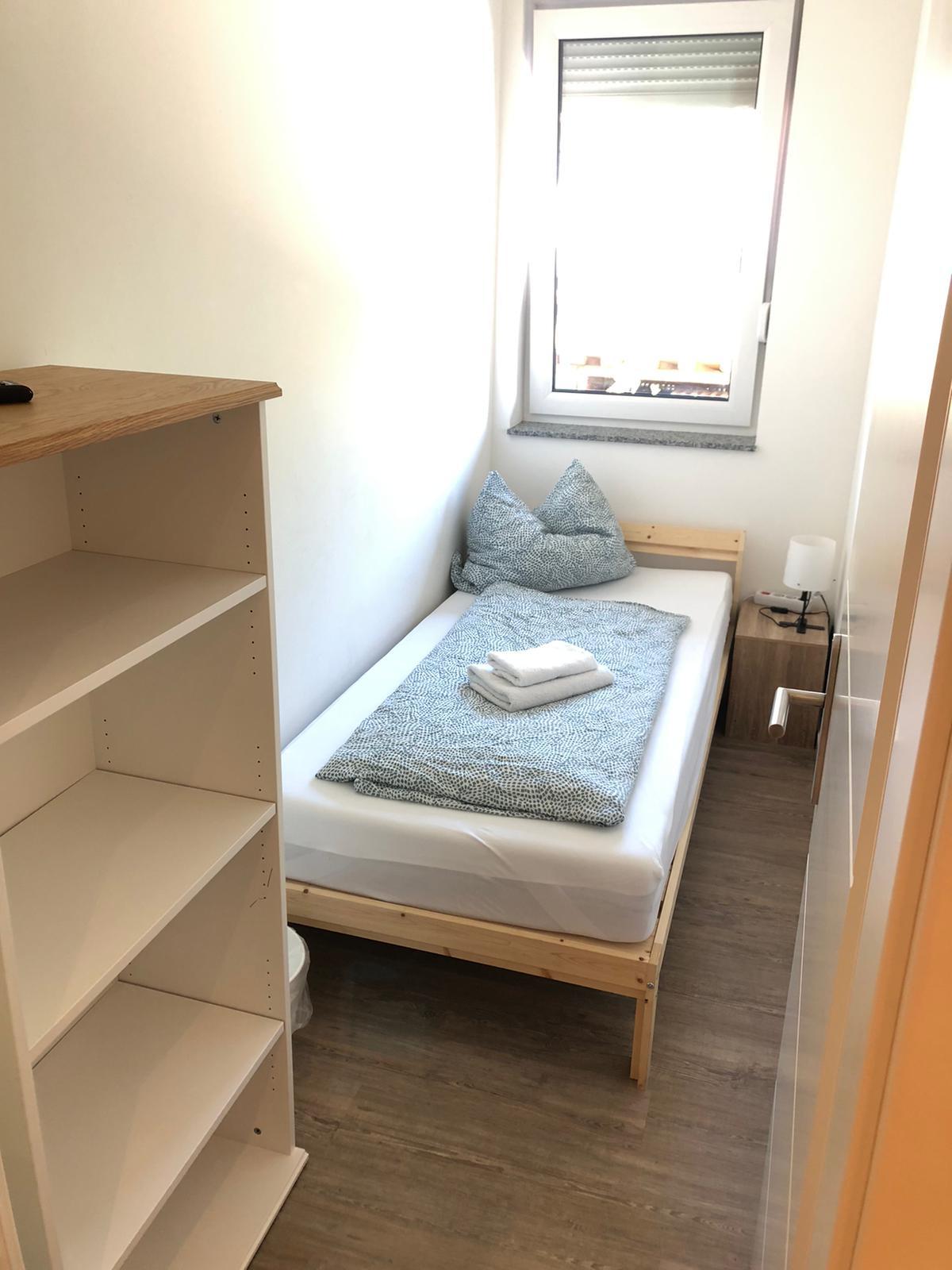 Einzelzimmer mit Holzbett, Nachttisch und Schreibtisch – Vilstal Apartment 2 in Reisbach/Altersberg