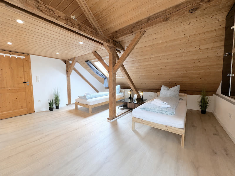 Helles Dachgeschoss-Zimmer mit Holzbalken, zwei Betten und freundlicher Holzausstattung