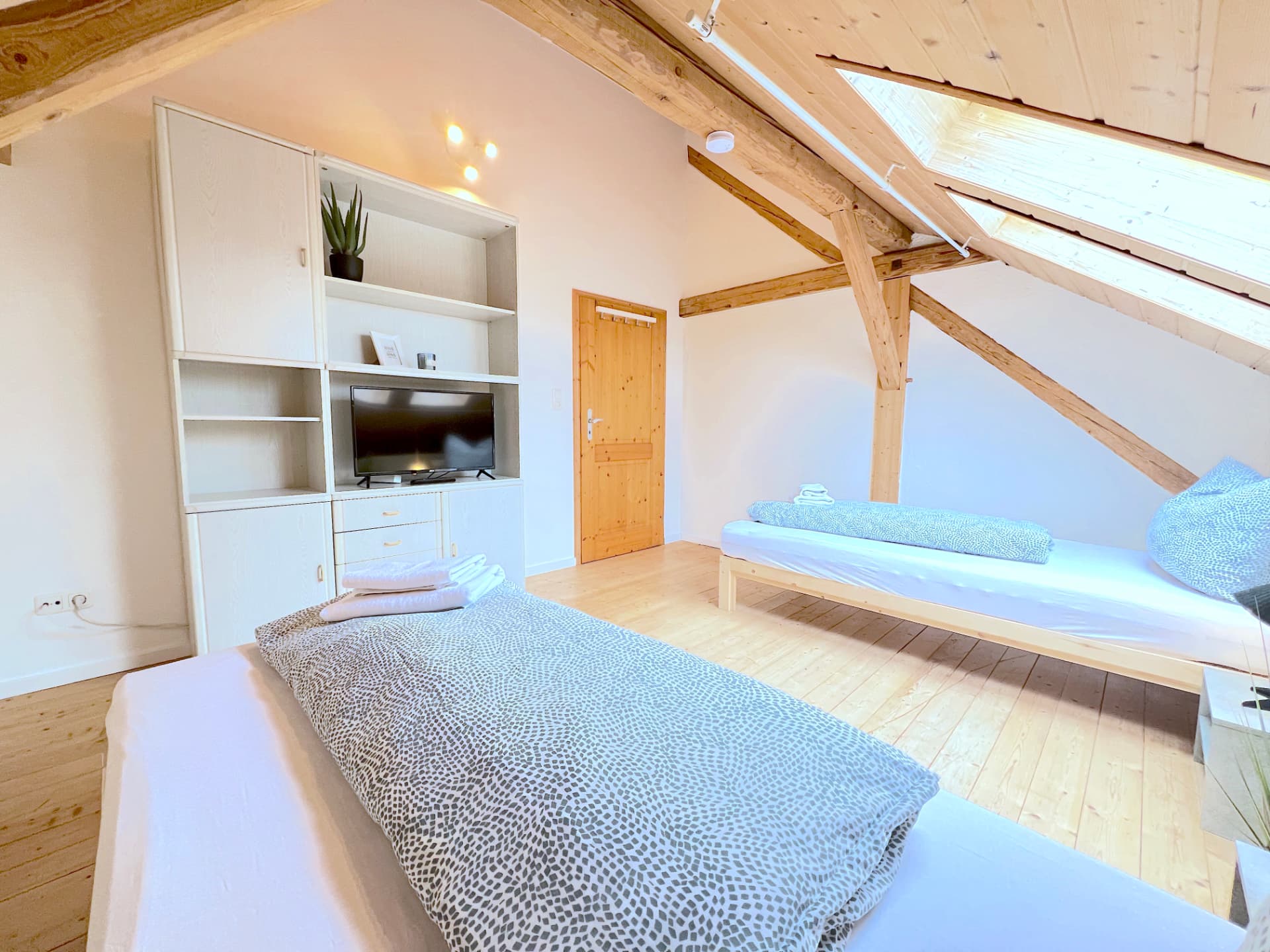 Apartment III in Dingolfing – Schlafzimmer mit zwei Betten, Schrankwand und TV