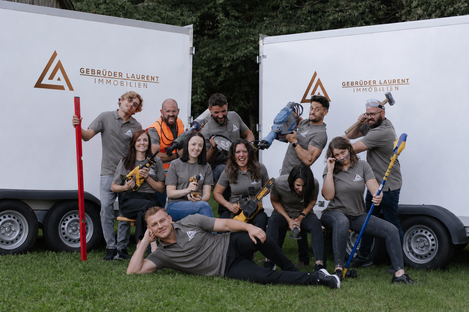 Gesamtes Team der Gebrüder Laurent Immobilien vor den Firmenanhängern